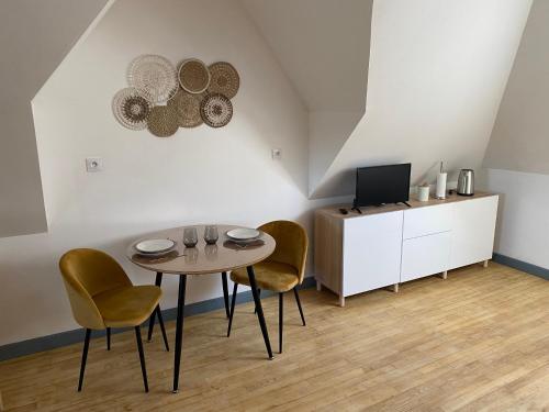 a dining room with a table and chairs and a tv at Studio Cocooning in Saint-Samson-sur-Rance