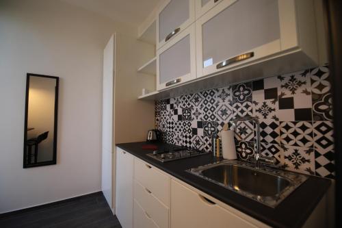 eine Küche mit einem Waschbecken und einer schwarzen Arbeitsplatte in der Unterkunft Le Cupole Design in Palermo