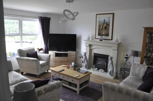 ein Wohnzimmer mit einem TV und einem Kamin in der Unterkunft Hillside Luxury Bed & Breakfast in Ballycastle