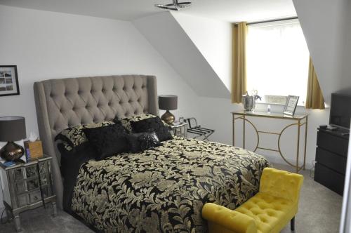 a bedroom with a large bed and a yellow chair at Hillside Luxury Bed & Breakfast in Ballycastle