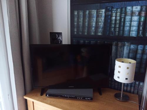 a television on a table with a lamp and books at Le Roi du Sundgau près de la Horse - Mooslargue in Mooslargue