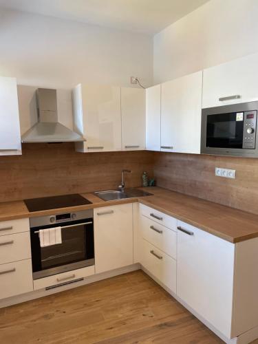 a kitchen with white cabinets and a sink and a microwave at Apartmány Elzet in Třeboň