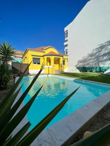 uma casa com piscina em frente a um edifício em Kali Vice Surf Villa em Costa da Caparica