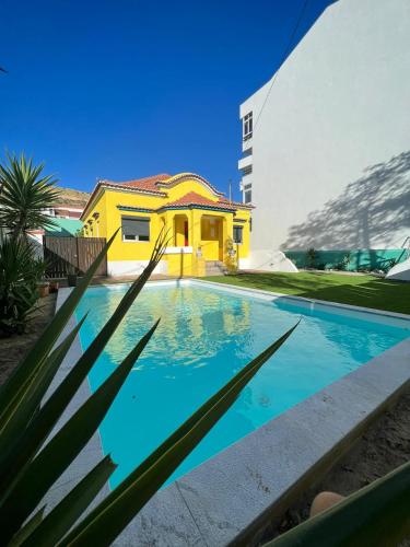una casa con piscina di fronte a un edificio di Kali Vice Surf Villa a Costa da Caparica