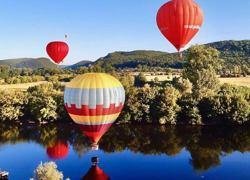 trois ballons à air chaud volant au-dessus d’une masse d’eau dans l'établissement Villa Mont Joie, à Beynac-et-Cazenac