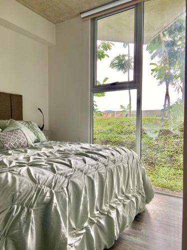 a bed in a bedroom with a large window at Cómodo y elegante apartamento en fabuloso condo! in San José