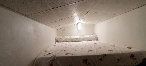 Una pequeña habitación blanca con una cama con flores. en Le paysage - Le studio PMR, en Arsac-en-Velay