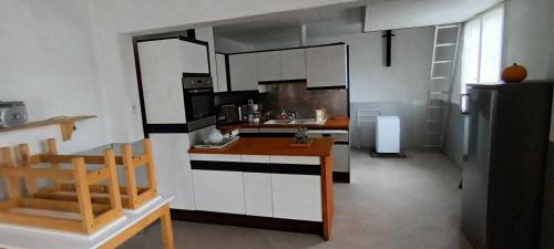 una cocina con armarios blancos y negros y una encimera en Le paysage - Le studio PMR, en Arsac-en-Velay