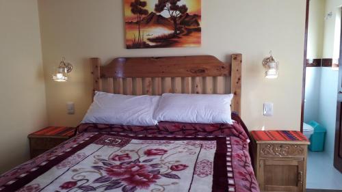 a bedroom with a bed with a wooden headboard at LA KANTUTA in Comunidad Yumani