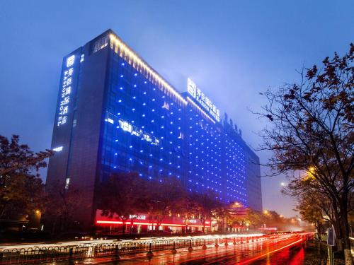 a tall building with blue lights on the side of it at Kasion International Hotel Yiwu in Yiwu
