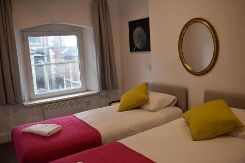 twee bedden in een kamer met een spiegel en een raam bij Florence House in Denbigh