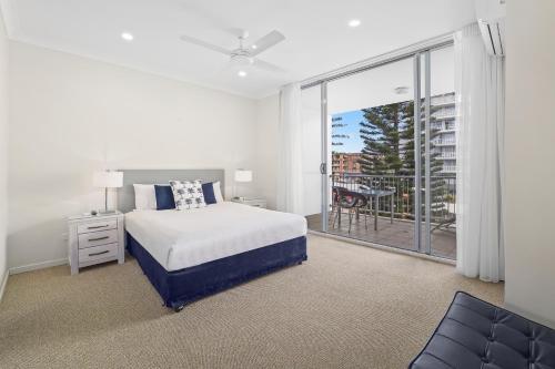 a white bedroom with a bed and a balcony at Macquarie Waters Boutique Apartment Hotel in Port Macquarie