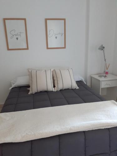 1 cama en un dormitorio con 2 cuadros en la pared en Departamento Nuevo en Cipolletti en Cipolletti