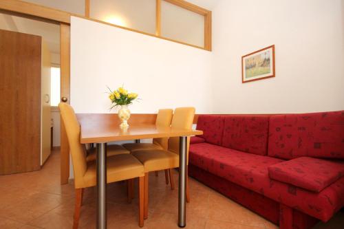 een woonkamer met een rode bank en een houten tafel bij Apartment Baska Voda 10027a in Baška Voda