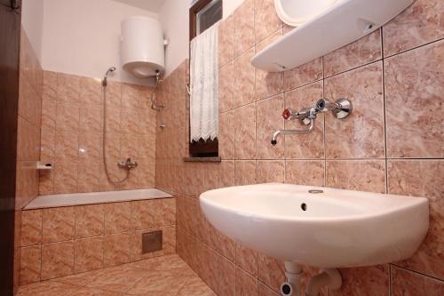 La salle de bains est pourvue d'un lavabo blanc et d'une douche. dans l'établissement Apartments with a parking space Povljana, Pag - 9405, à Povljana