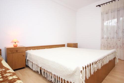 a bedroom with a white bed and a window at Apartments with a parking space Povljana, Pag - 9405 in Povljana