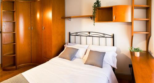 a bedroom with a bed with white sheets and pillows at Sestao, Vivienda Turística Renovada con Terraza y WIFI in Sestao