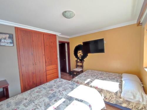 a bedroom with two beds and a flat screen tv at Casatodosantos in Cuenca