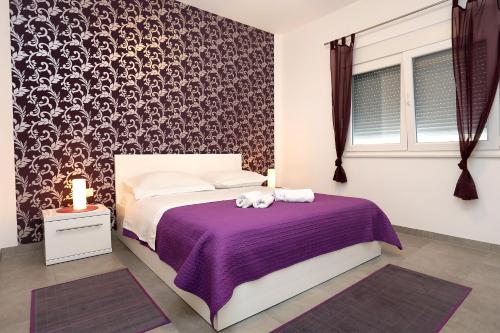 a bedroom with a bed with a purple bedspread at Apartments by the sea Duce, Omis - 10304 in Duće