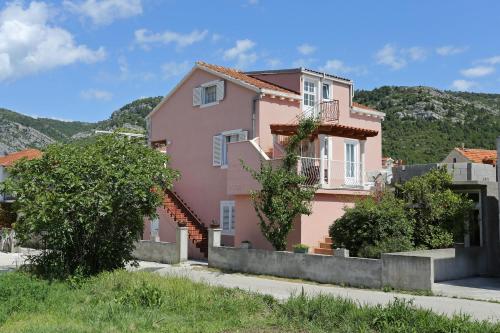a pink house with mountains in the background at Apartments by the sea Zuljana, Peljesac - 10112 in Žuljana