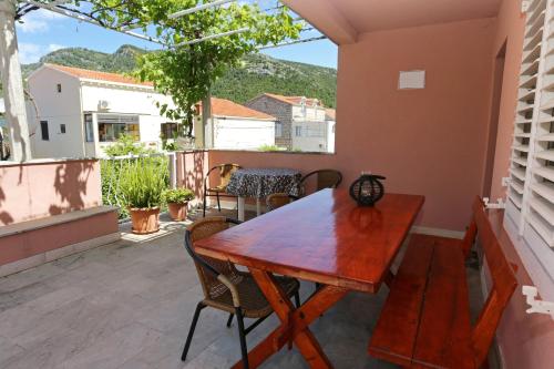 uma mesa de madeira e cadeiras numa varanda em Apartments by the sea Zuljana, Peljesac - 10112 em Žuljana