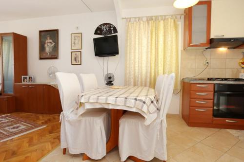 a kitchen with a table and white chairs in a room at Apartment Zuljana 10112a in Žuljana