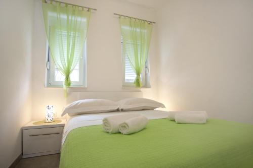a white bedroom with a green bed with two pillows at Apartment Duce 10304c in Duće