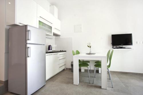 a white kitchen with a table and a refrigerator at Apartment Duce 10304c in Duće