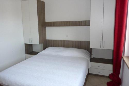 a small bedroom with a white bed and white cabinets at Apartment Drace 10127c in Drače