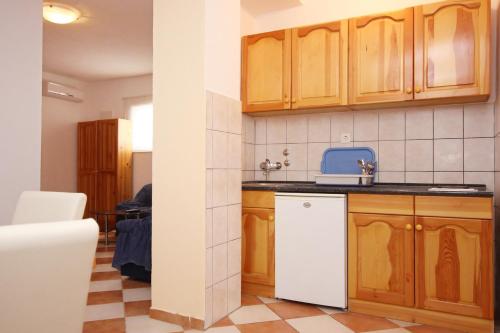 a kitchen with wooden cabinets and a white dishwasher at Apartments and rooms with parking space Orebic, Peljesac - 10191 in Orebić