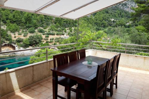 una mesa y sillas en un balcón con vistas en Secluded fisherman's cottage Cove Bacva, Korcula - 9475 en Korčula