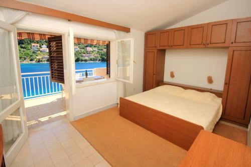ein Schlafzimmer mit einem Bett und einem großen Fenster in der Unterkunft Apartments by the sea Brna, Korcula - 10057 in Smokvica