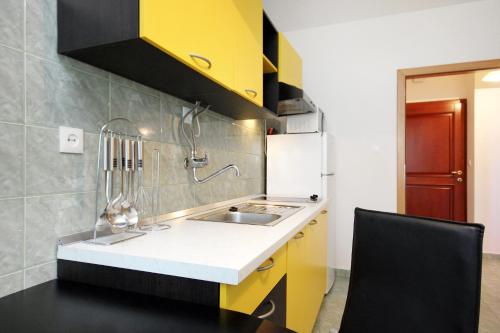 kuchnia z żółtymi szafkami i zlewem w obiekcie Apartment Razanj 10318a w Rogoznicy