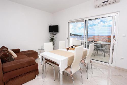 a living room with a table and chairs and a couch at Apartments by the sea Seget Vranjica, Trogir - 10328 in Seget Vranjica