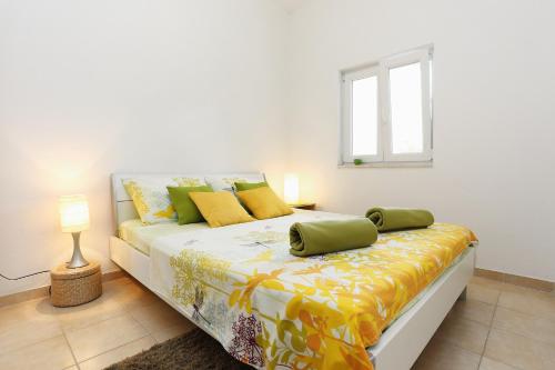 una camera da letto con un letto con cuscini gialli e verdi di Apartments by the sea Seget Vranjica, Trogir - 10328 a Seget Vranjica
