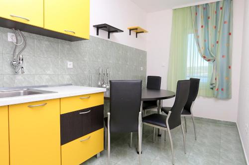 kuchnia ze stołem z krzesłami i żółtymi szafkami w obiekcie Apartments by the sea Razanj, Rogoznica - 10318 w Rogoznicy