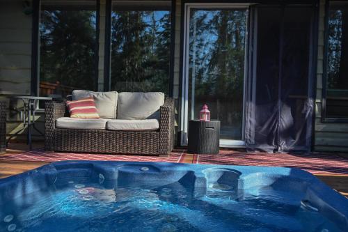 a hot tub in the middle of a patio with a couch at Auberge Kicking Horse Guest House in Golden