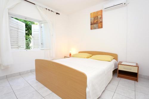 a white bedroom with a bed and a window at Apartments with a parking space Orebic, Peljesac - 10102 in Orebić