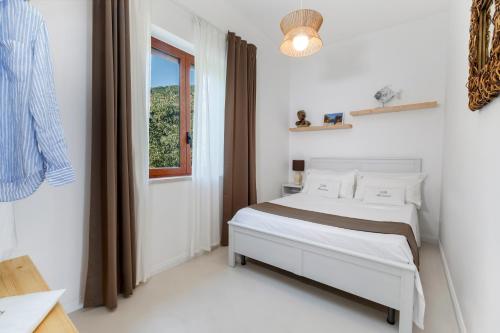 a white bedroom with a bed and a window at Villa Marianna in Massa Lubrense
