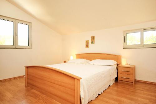 a bedroom with a large bed and two windows at Apartment Prizba 10061a in Prizba