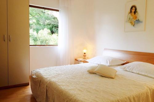 a bedroom with a large white bed with a window at Family friendly seaside apartments Prizba, Korcula - 10061 in Prizba