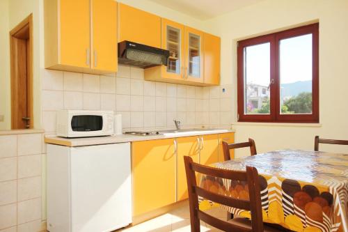 a kitchen with yellow cabinets and a table with a microwave at Apartments with a parking space Orebic, Peljesac - 10157 in Orebić