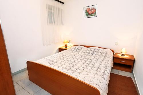 a small bedroom with a bed and two night stands at Apartments by the sea Viganj, Peljesac - 10140 in Viganj