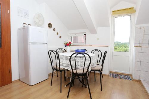 uma cozinha com uma mesa e cadeiras e um frigorífico em Apartments by the sea Sreser, Peljesac - 10105 em Janjina
