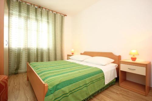 a bedroom with a bed with a green and white blanket at Apartments with a parking space Orebic, Peljesac - 10159 in Orebić
