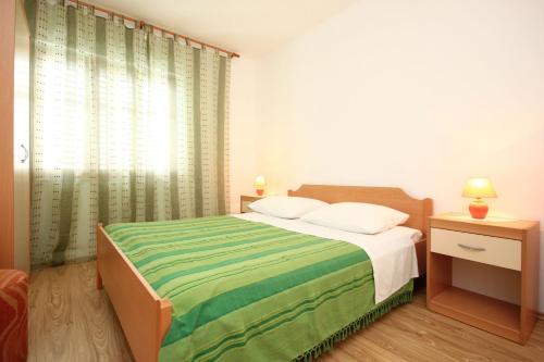 a bedroom with a bed with a green and white blanket at Apartments with parking space Orebic, Peljesac - 10159 in Orebić