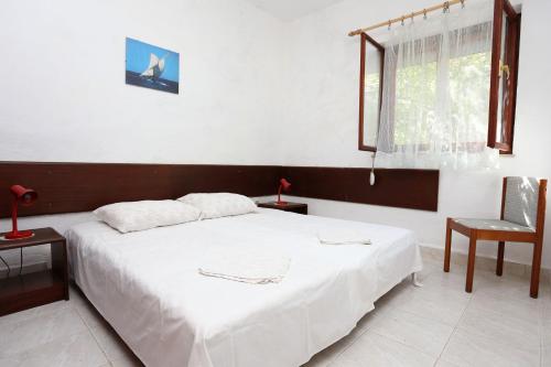 ein Schlafzimmer mit einem weißen Bett und einem Stuhl in der Unterkunft Apartments by the sea Sreser, Peljesac - 10227 in Janjina