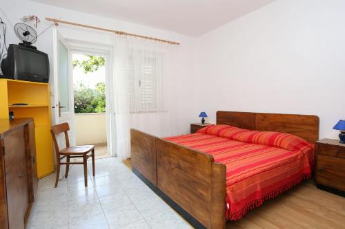 ein Schlafzimmer mit einem Bett, einem TV und einem Stuhl in der Unterkunft Apartment Viganj 10116c in Viganj
