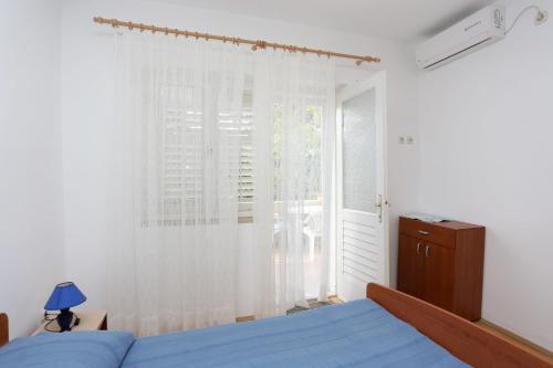 Un dormitorio con una cama azul y una ventana en Apartment Viganj 10116d, en Viganj