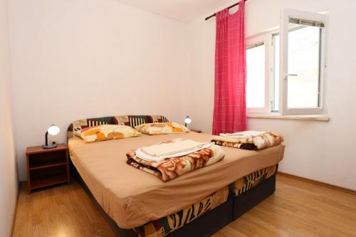 a bedroom with a bed with a red curtain and a window at Apartments by the sea Zuljana, Peljesac - 10207 in Žuljana